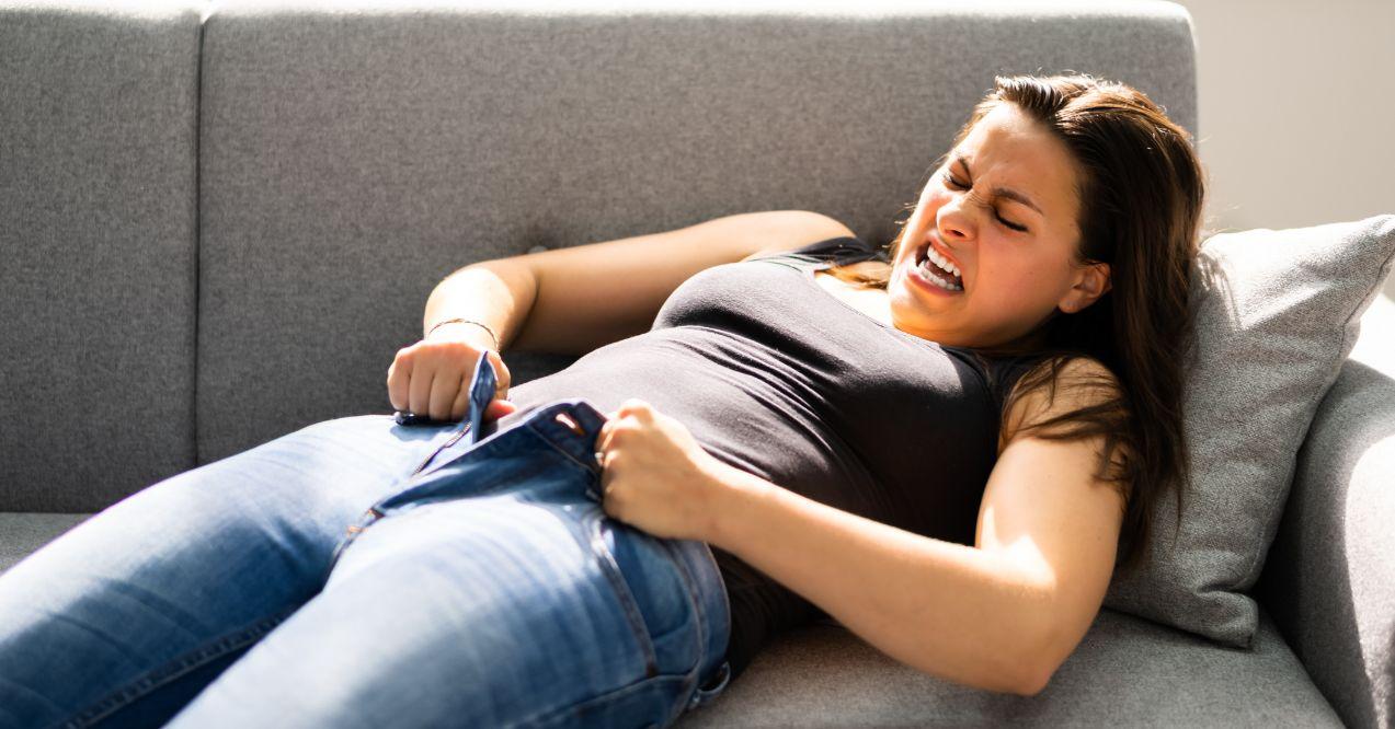 Woman struggling to button her jeans
