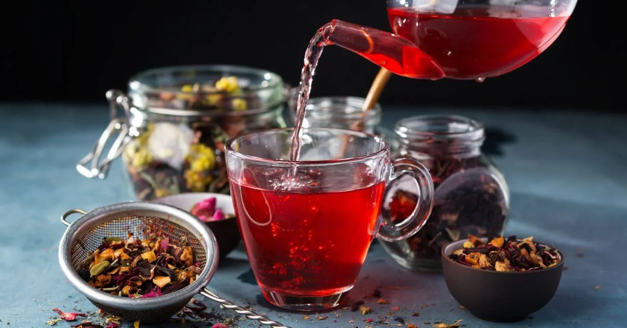 Pouring best detox teas for liver into a glass cup with loose tea.