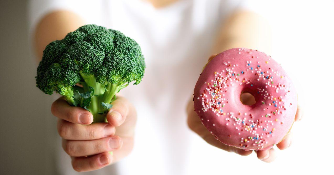 a person is holding a broccoli and a donut in separate hands