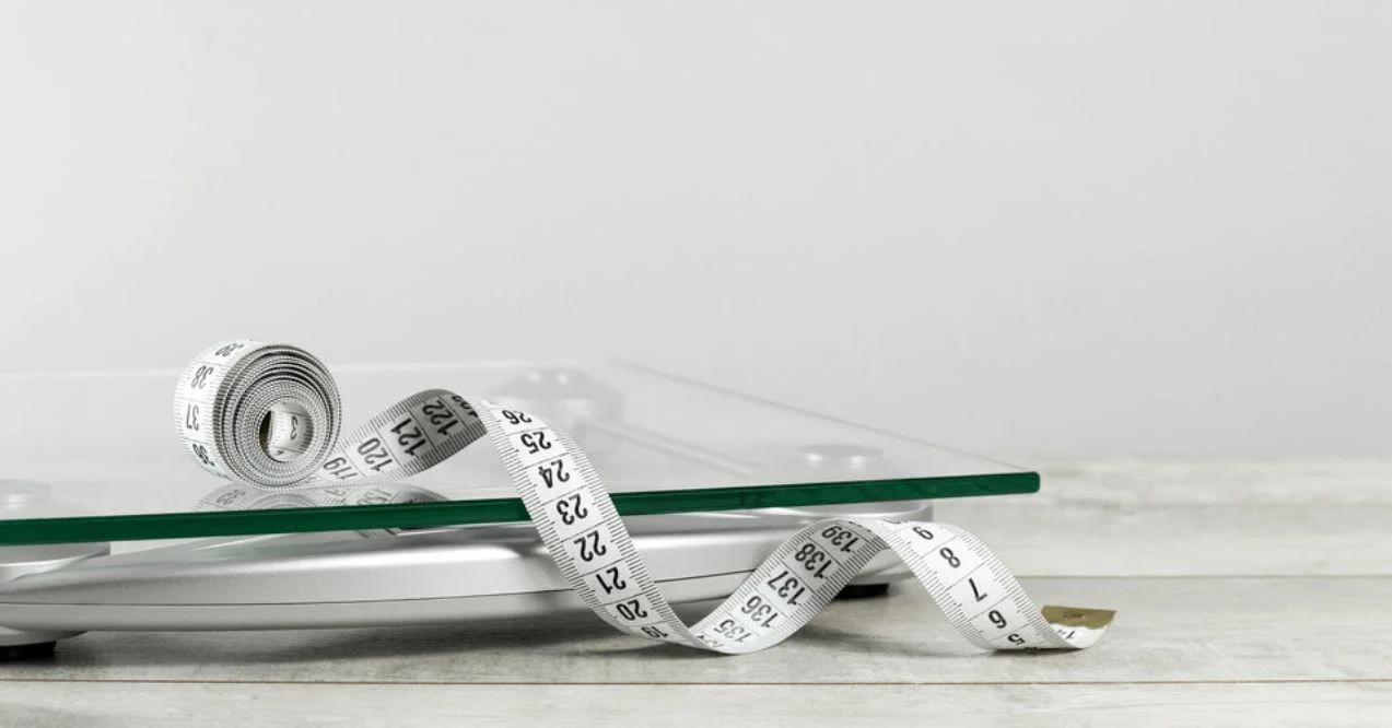 White tape measure on top of glass weighing scale