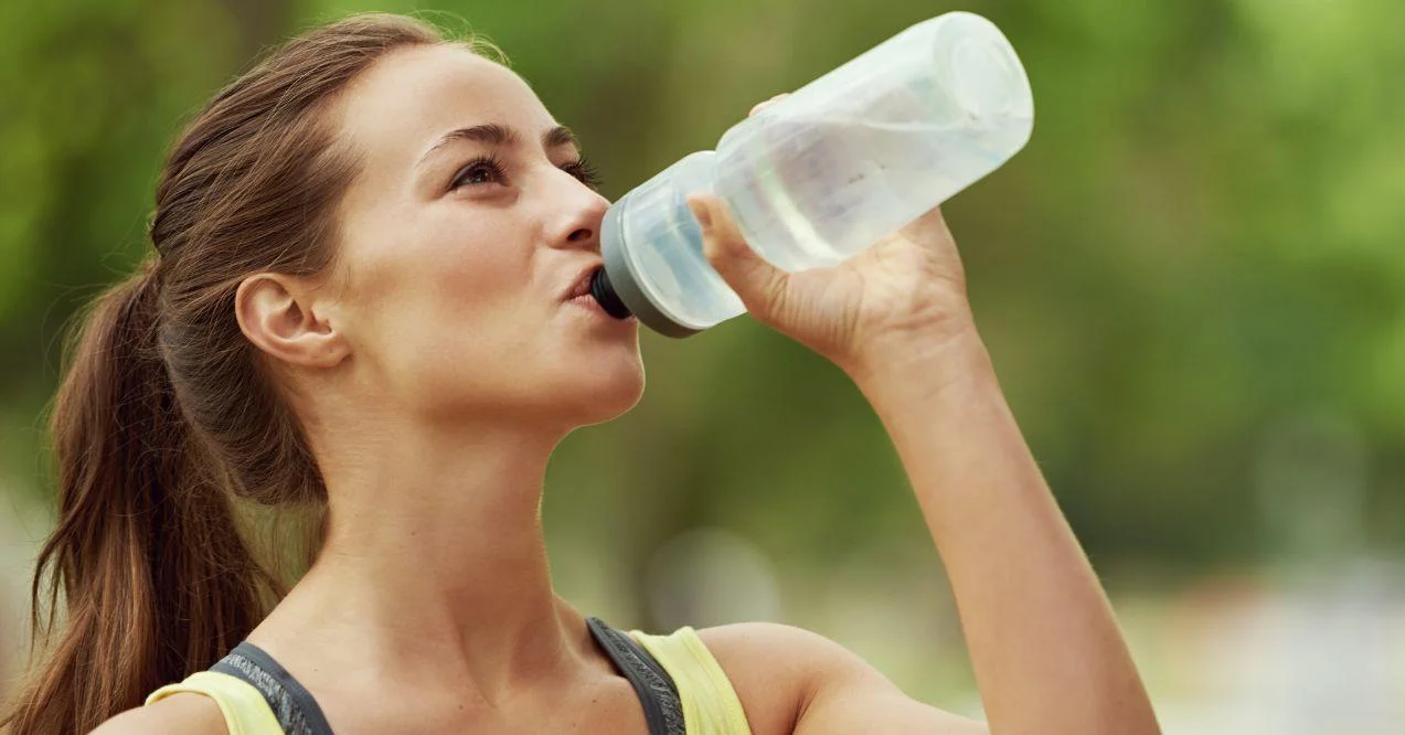 woman is drinking water from a flask