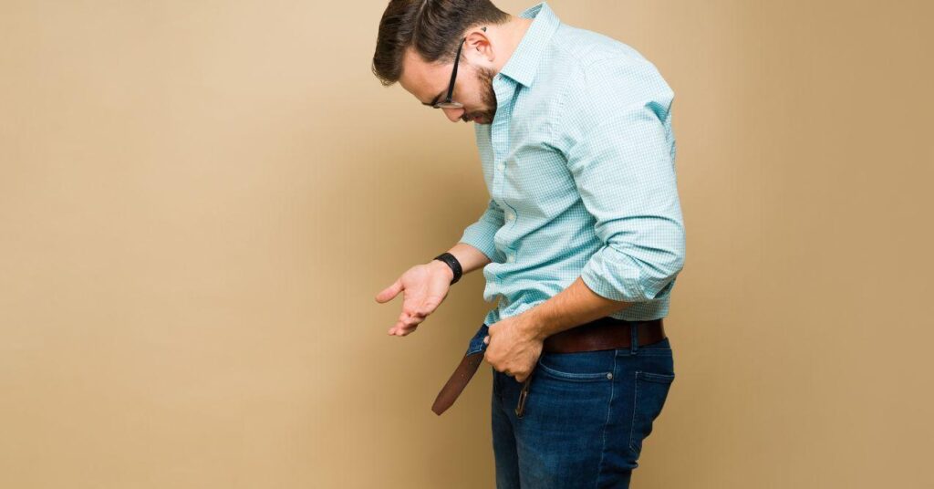 a man is looking at his chest with his belt unbuckled