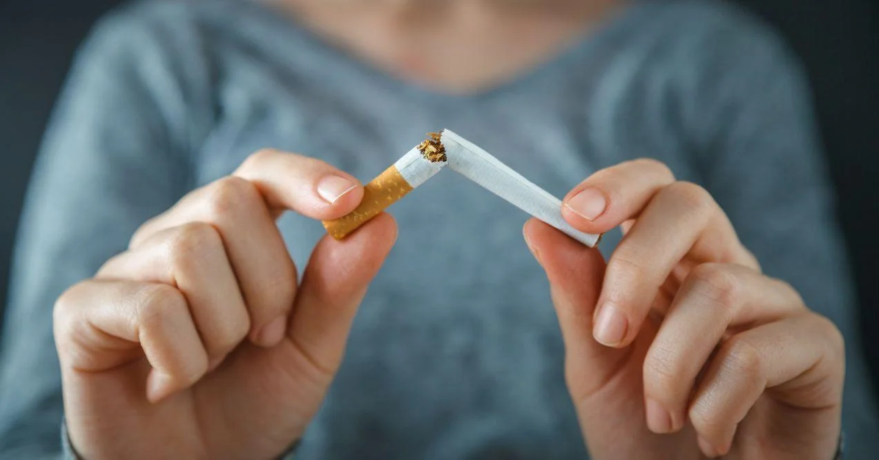 a woman is breaking a cigarette in half