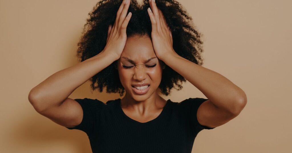 a woman is holding both of her hands on her head due to a migraine
