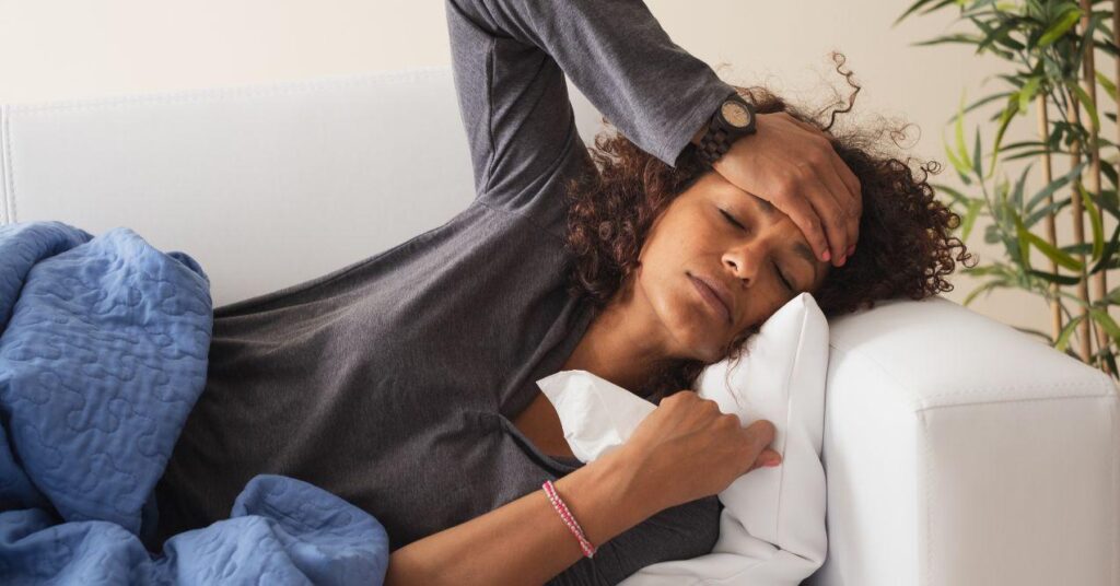 a woman is lying down and holding her hand on her head because of the fever