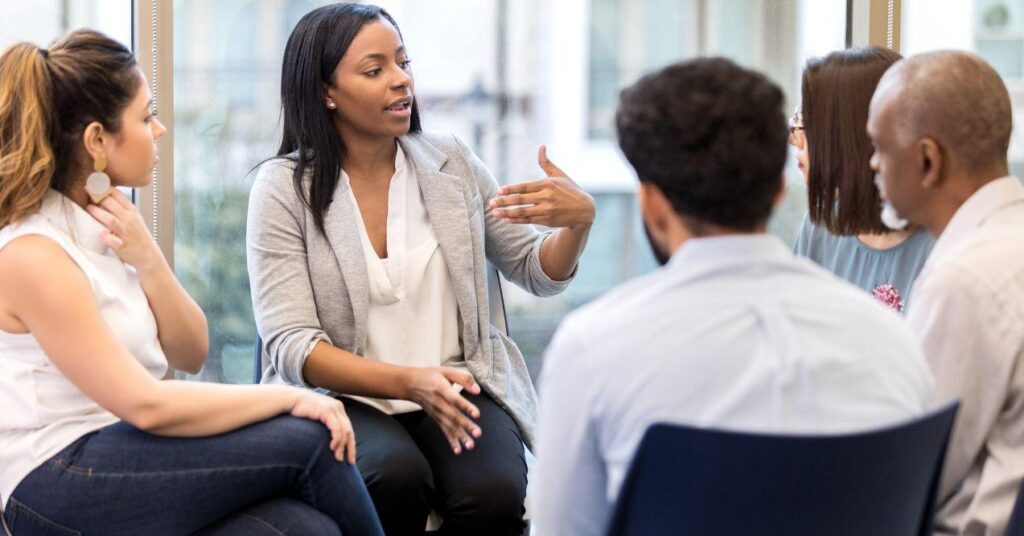 a woman is speaking with a group of people