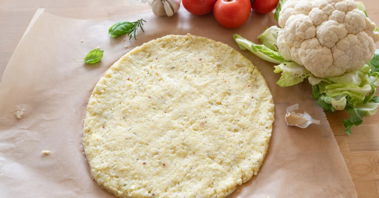 Cauliflower pizza crust with fresh ingredients on parchment paper