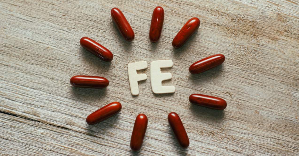 Dark red sleek capsules pills on wooden background