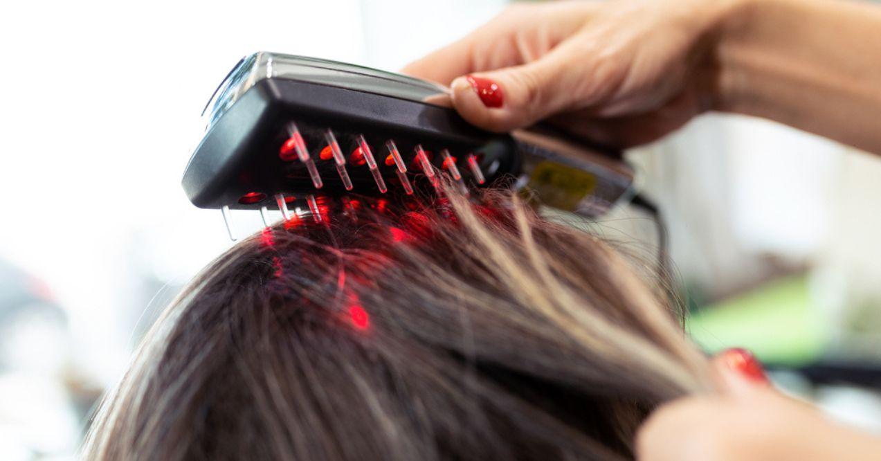 Hairdresser doing a hair regrowth treatment with ultrasonic and infrared laser comb