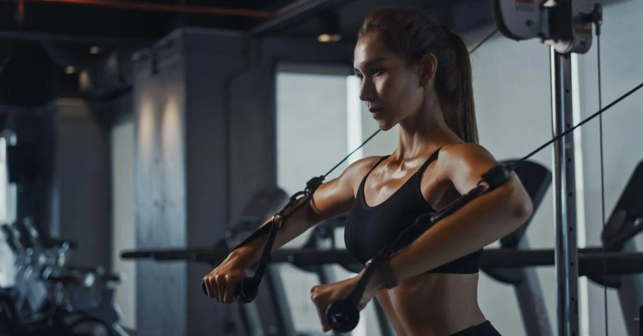 Sporty woman exercising on multi station at gym