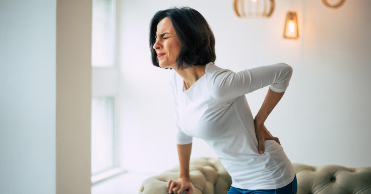 Woman is holding her lower back and experiencing pain