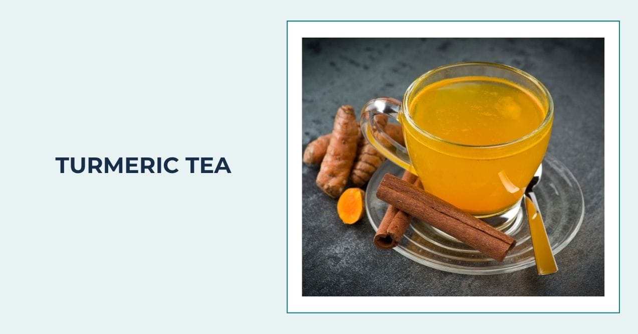 Glass cup of turmeric tea with fresh turmeric roots and cinnamon sticks on dark background.