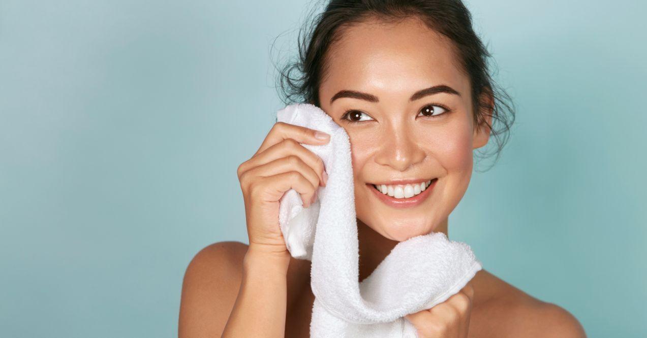 a woman is cleaning her face with a white towel