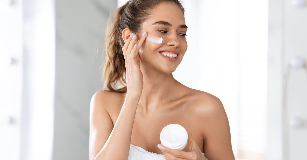 a woman is moisturizing her face with face cream