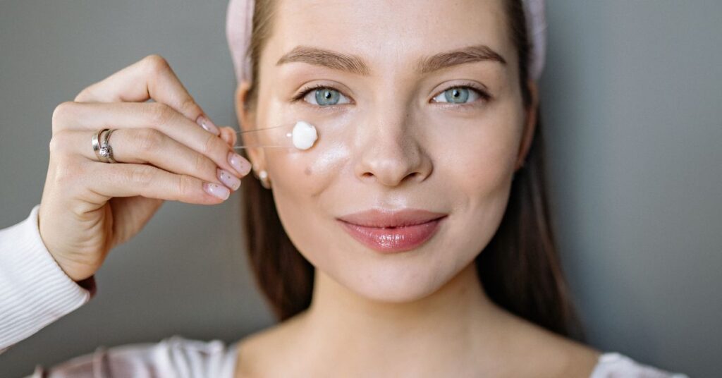 a woman is moisturizing her face with face cream