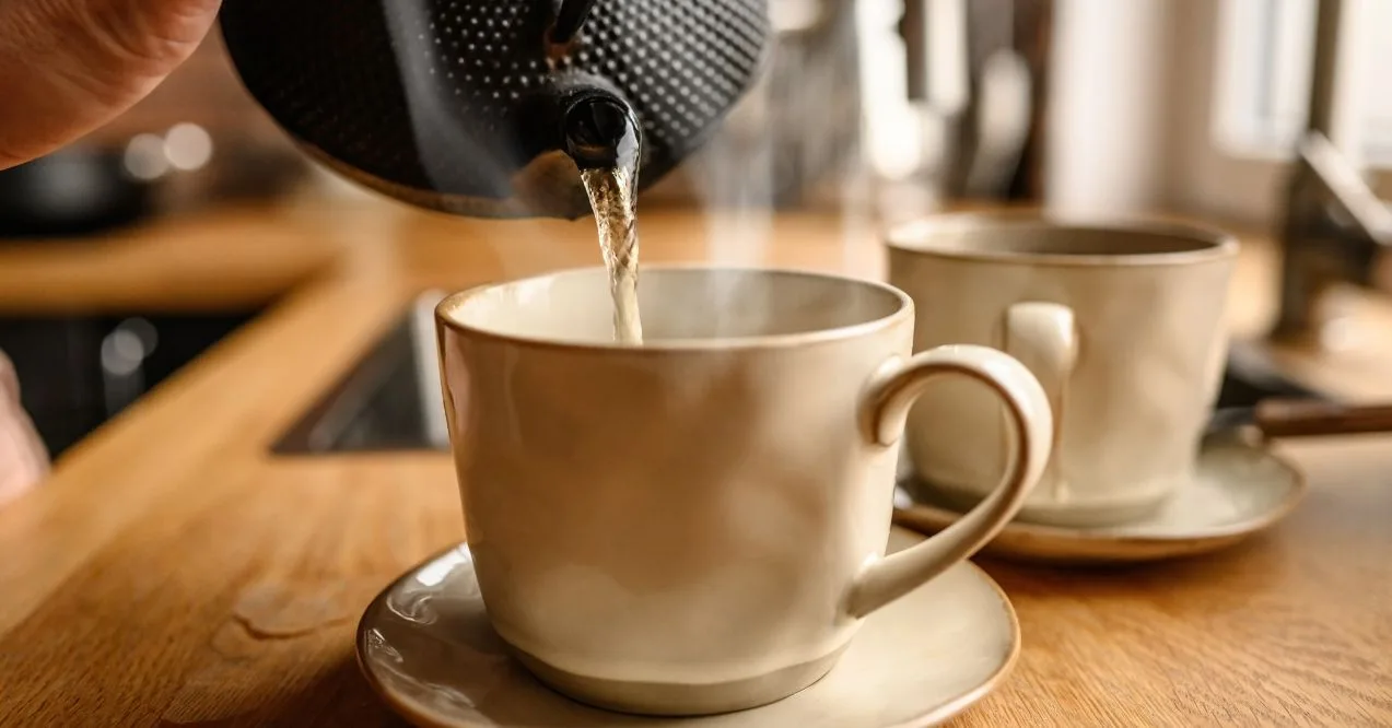 Pouring hot water into ceramic tea cup with steam resembling best teas for inflammation