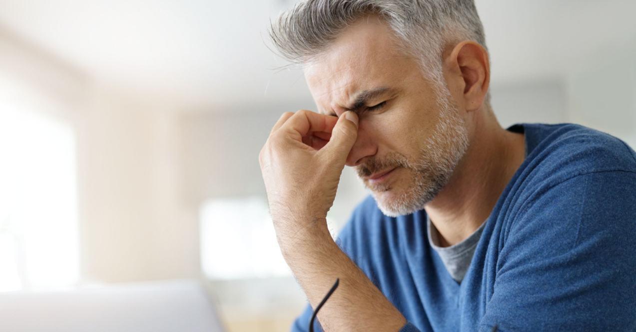 Man at home having a headache in front of laptop