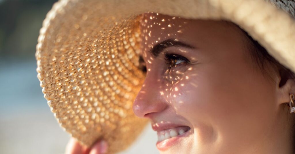 a woman is protecting herself from sun with a hat