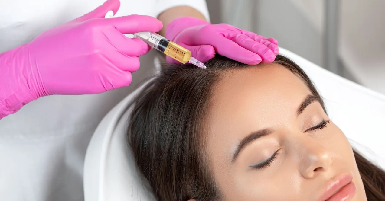 healthcare professional in pink gloves administering an PRP injection to a woman's forehead
