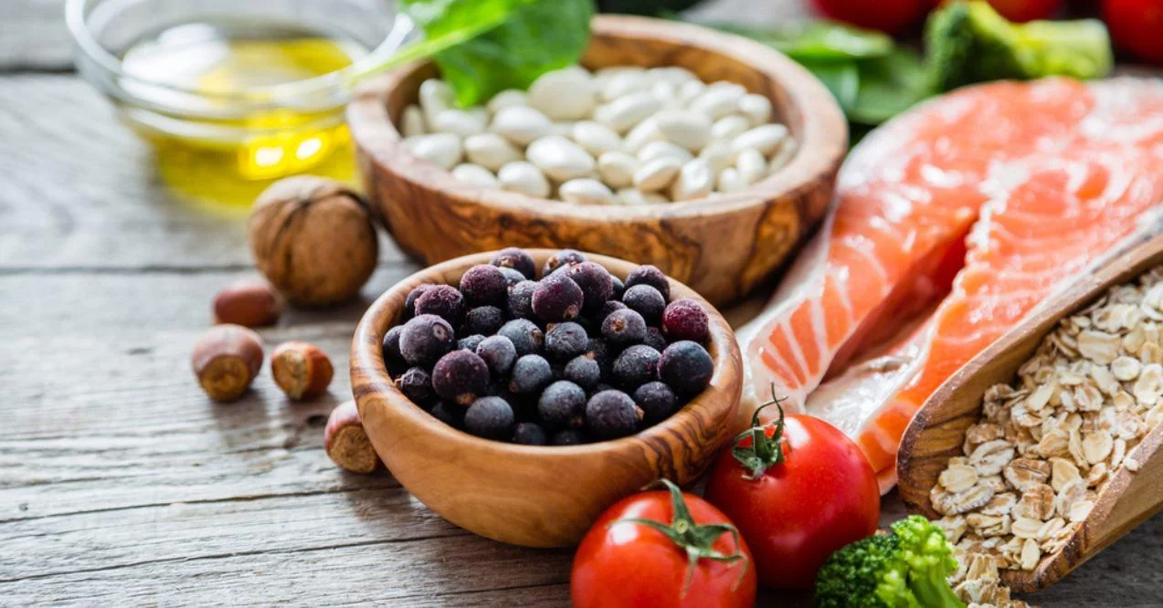 Assorted healthy foods including fruits, vegetables, nuts, fish, and oats