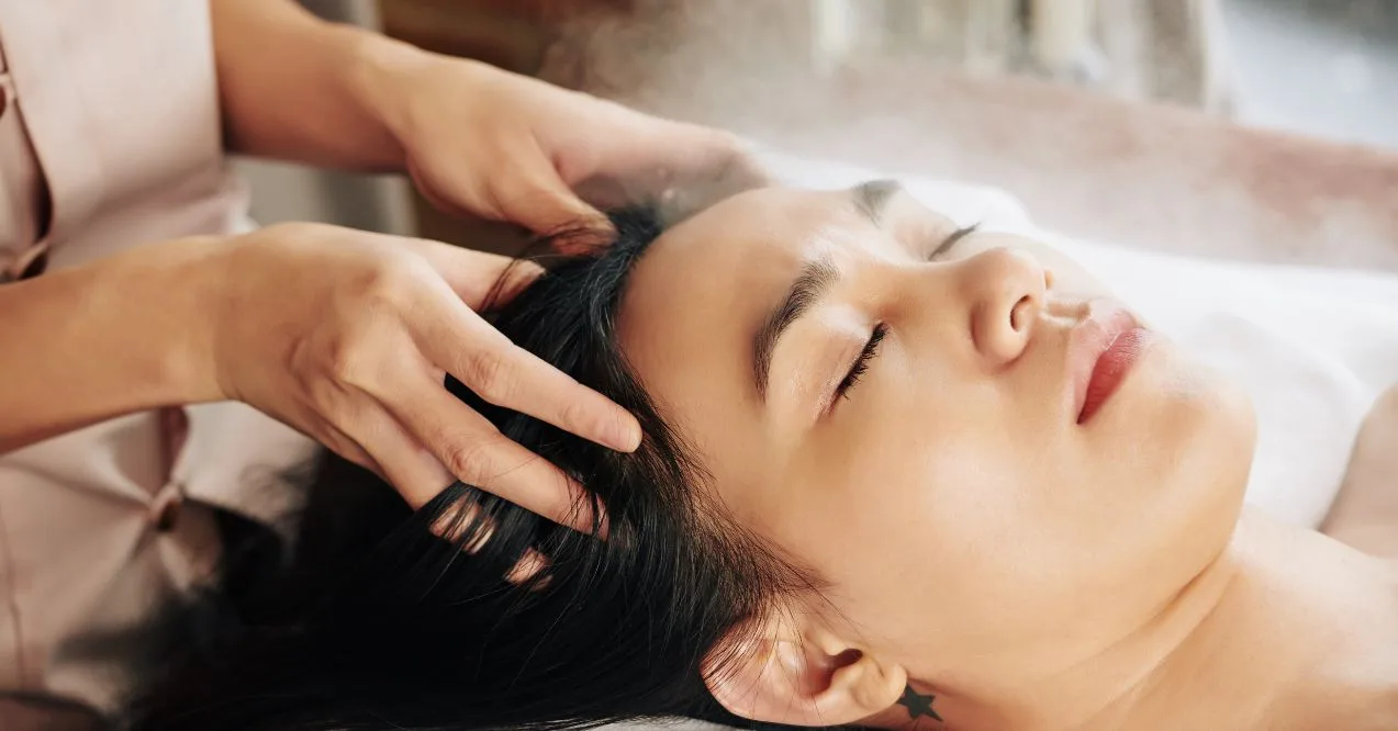relaxed woman receiving a scalp massage in a serene setting