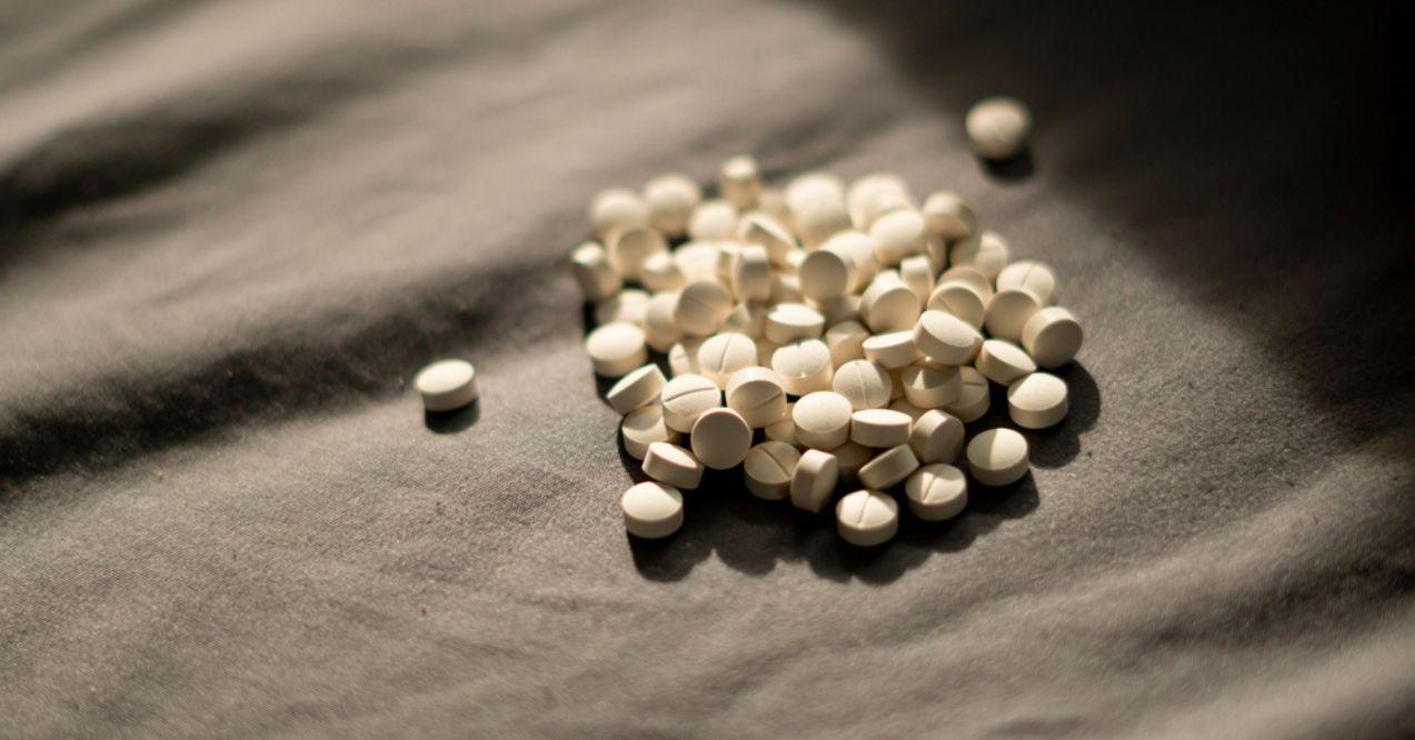 A pile of selenium pills on a dark fabric surface