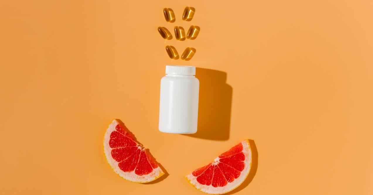 A white pill bottle with vitamin c capsules floating above it