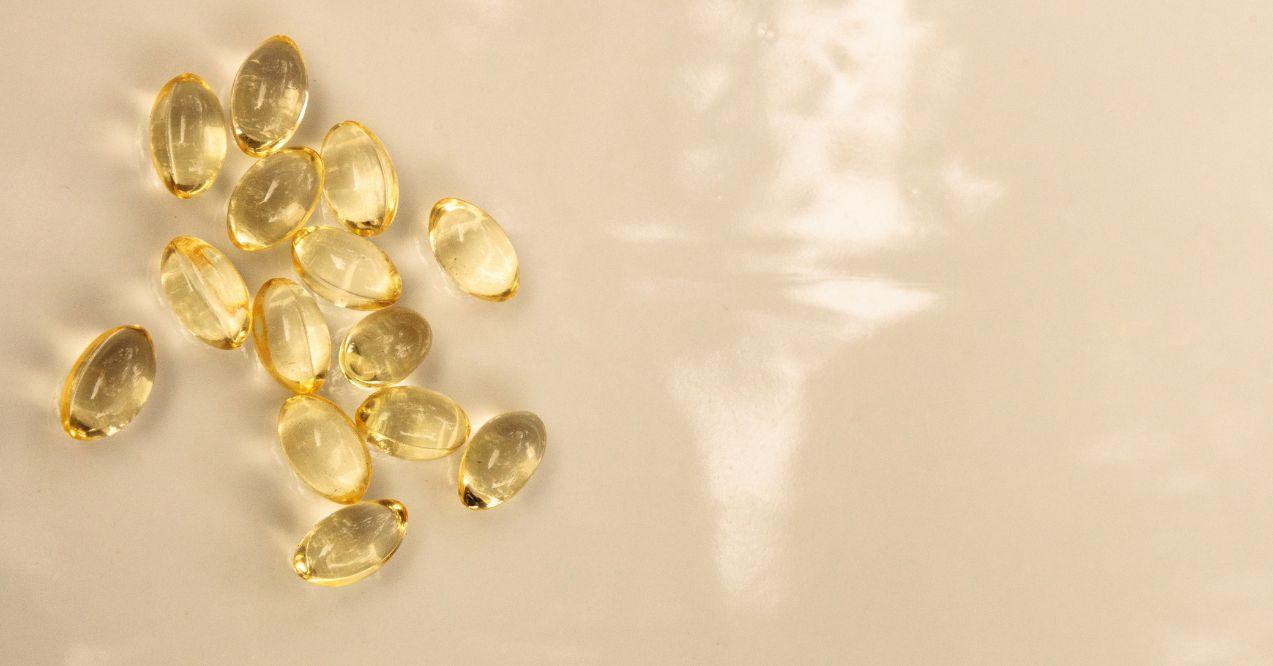 Transparent vitamin E capsules scattered on a creamy surface