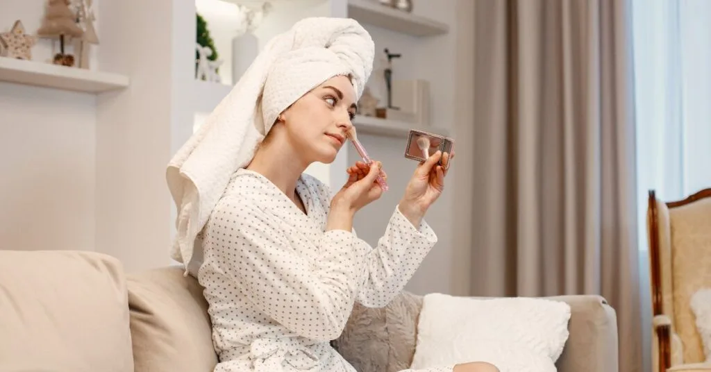 a woman with a towel on a head is putting on her make up