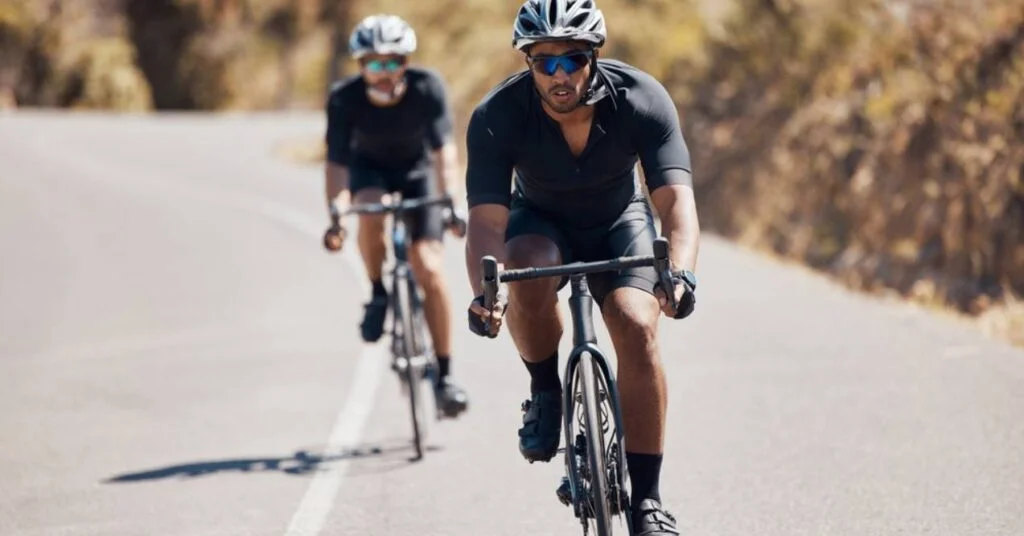Two fitness men cycling bike on mountain road