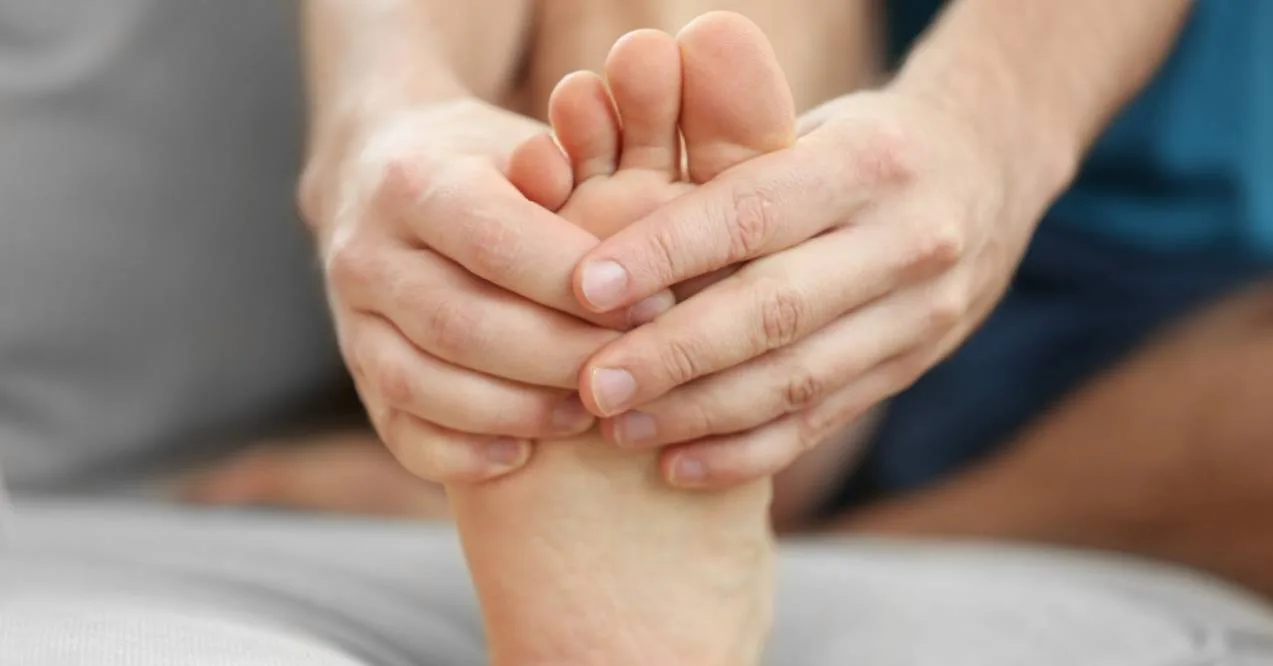 A close-up of two hands gently holding and encircling a bare foot