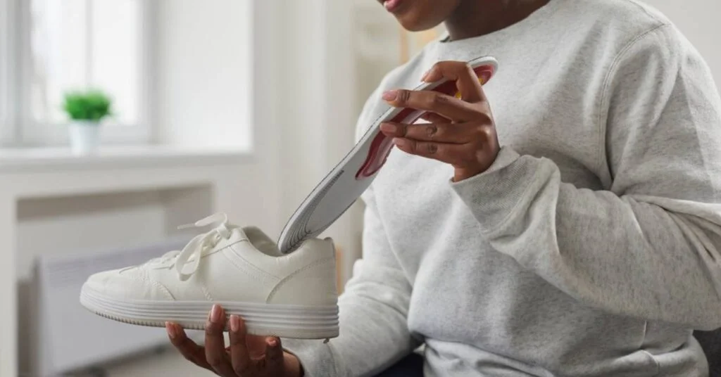 African American woman putting orthopedic insole into shoe