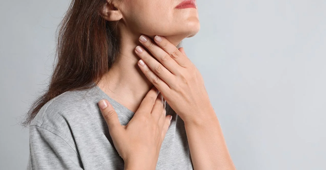 Mature woman doing thyroid self examination on light background, closeup featured image