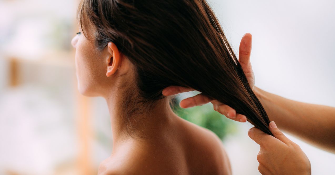 a woman with long dark hair receiving a hair treatment with olive oil to enhance hair growth and health.