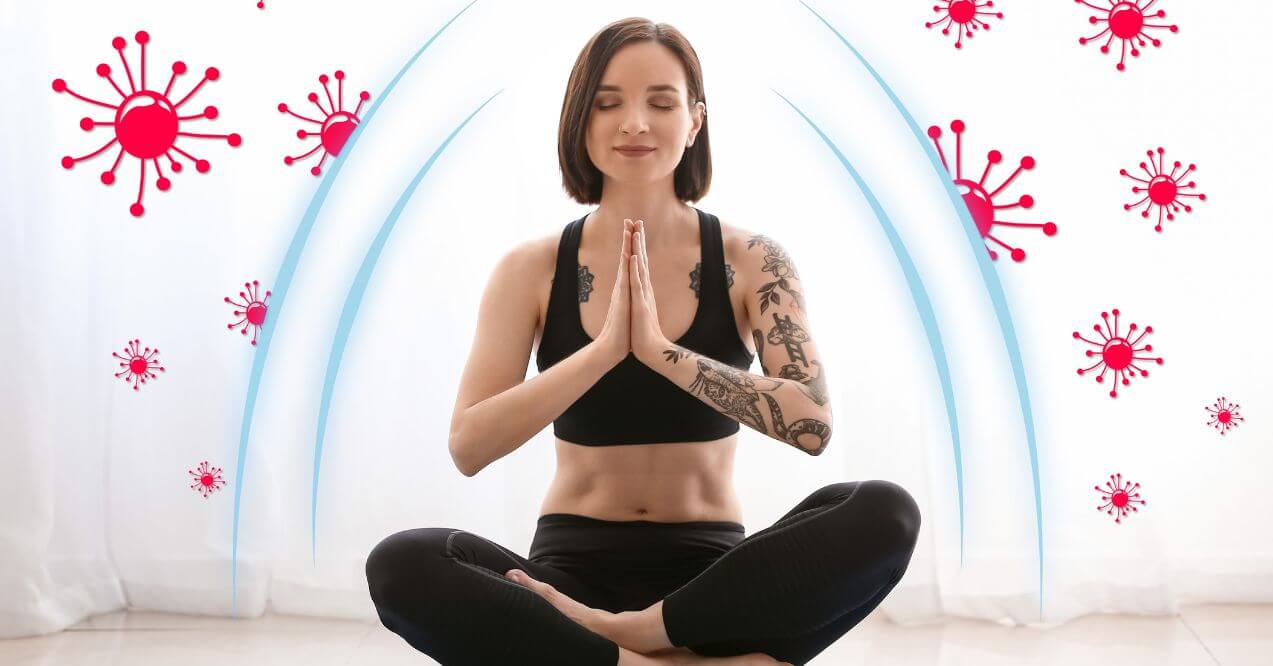 A woman in a meditative pose, sitting cross-legged with hands in a prayer position, surrounded by a visual representation of viruses being blocked by an invisible shield, symbolizing immune protection.