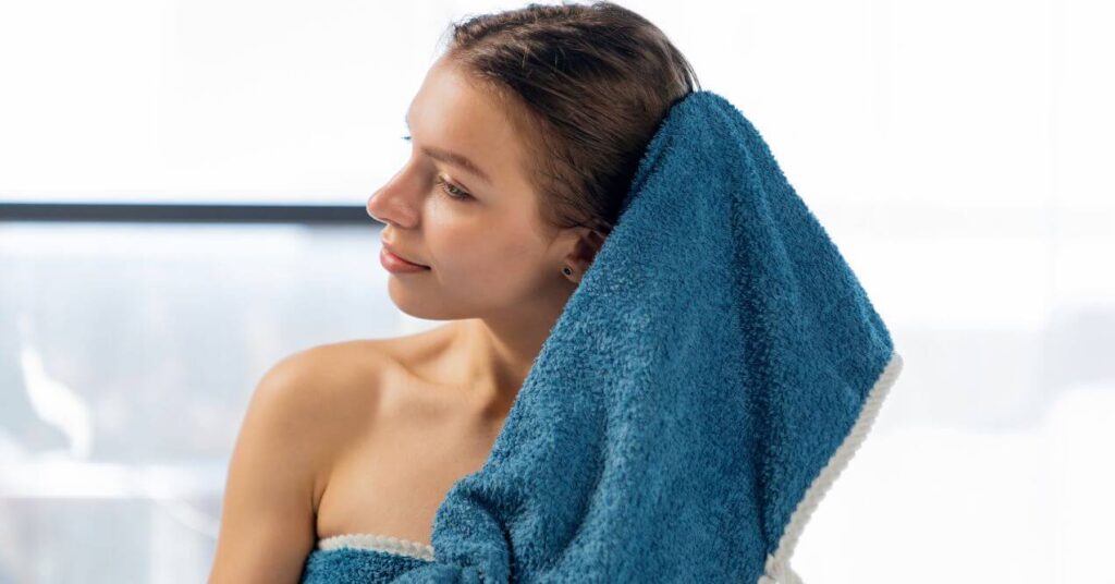 A young woman drying her hair with a towel after the shower.