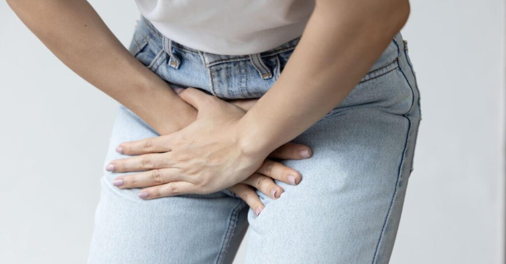 A woman laying one hand on the other hand on her uterus because of menstrual pain.