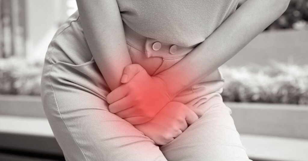 woman is curled up holding her bladder because of the pain of urinary tract infection.