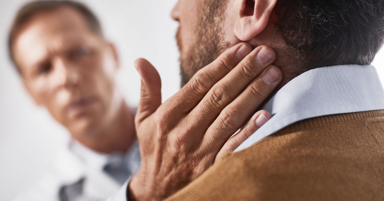 Doctor examining a man's neck, checking for swollen lymph nodes as part of a medical evaluation.