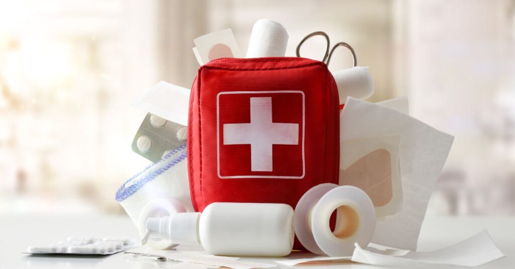 A red first aid kit placed on a table with essential medical supplies such as bandages, ointments, and medications.