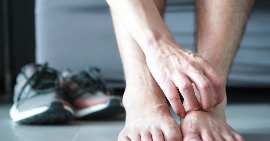 A person scratching the skin on their foot, indicating discomfort or irritation possibly from a fungal infection.