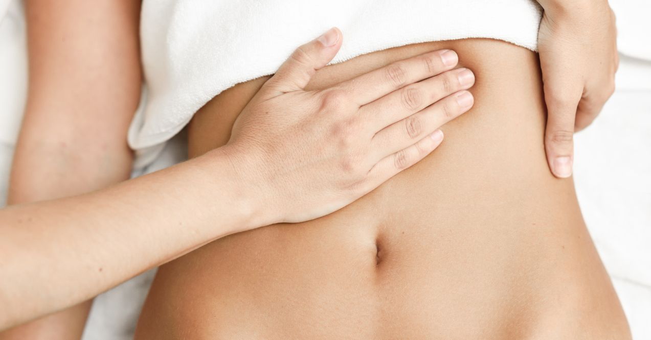 Hands performing an ENS massage on the abdominal area to relieve tension.