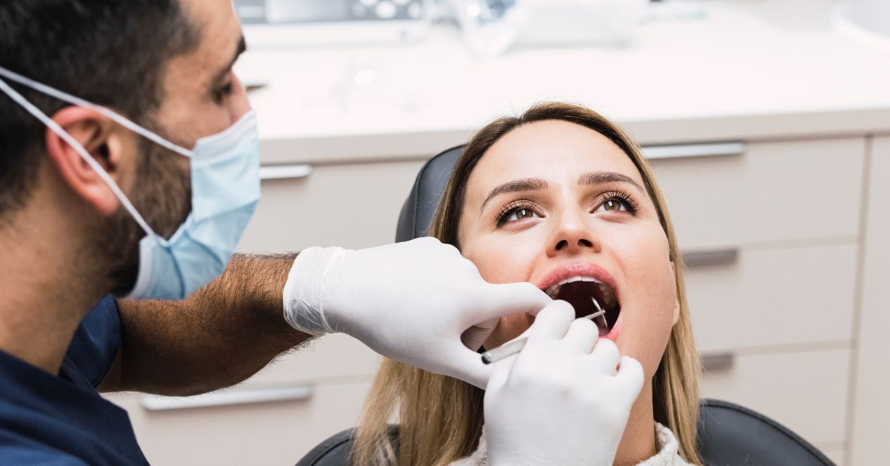 A dentist examining a patient's teeth during a routine dental check-up.