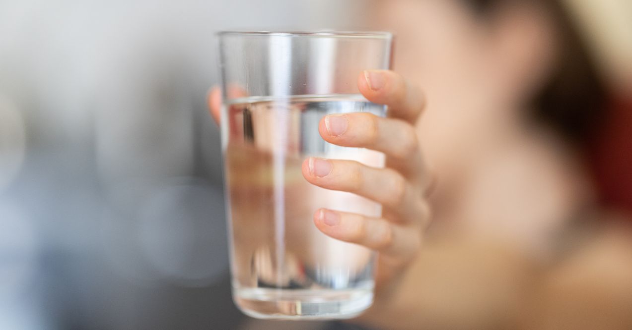 Close-up of a person holding a glass of water.