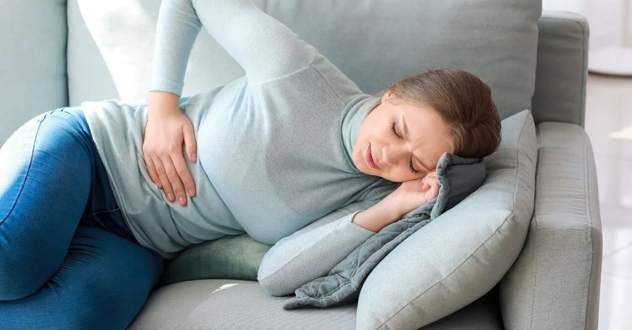 Woman holding her side, displaying signs of liver discomfort and fatigue.
