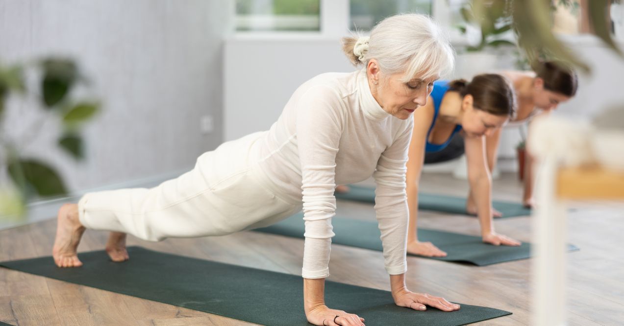 Senior woman doing the cannon pose in a yoga session at a studio.