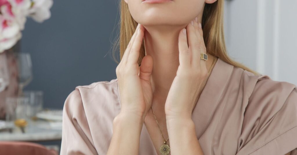 Woman touching her neck, indicating discomfort or swelling in the lymph nodes area.