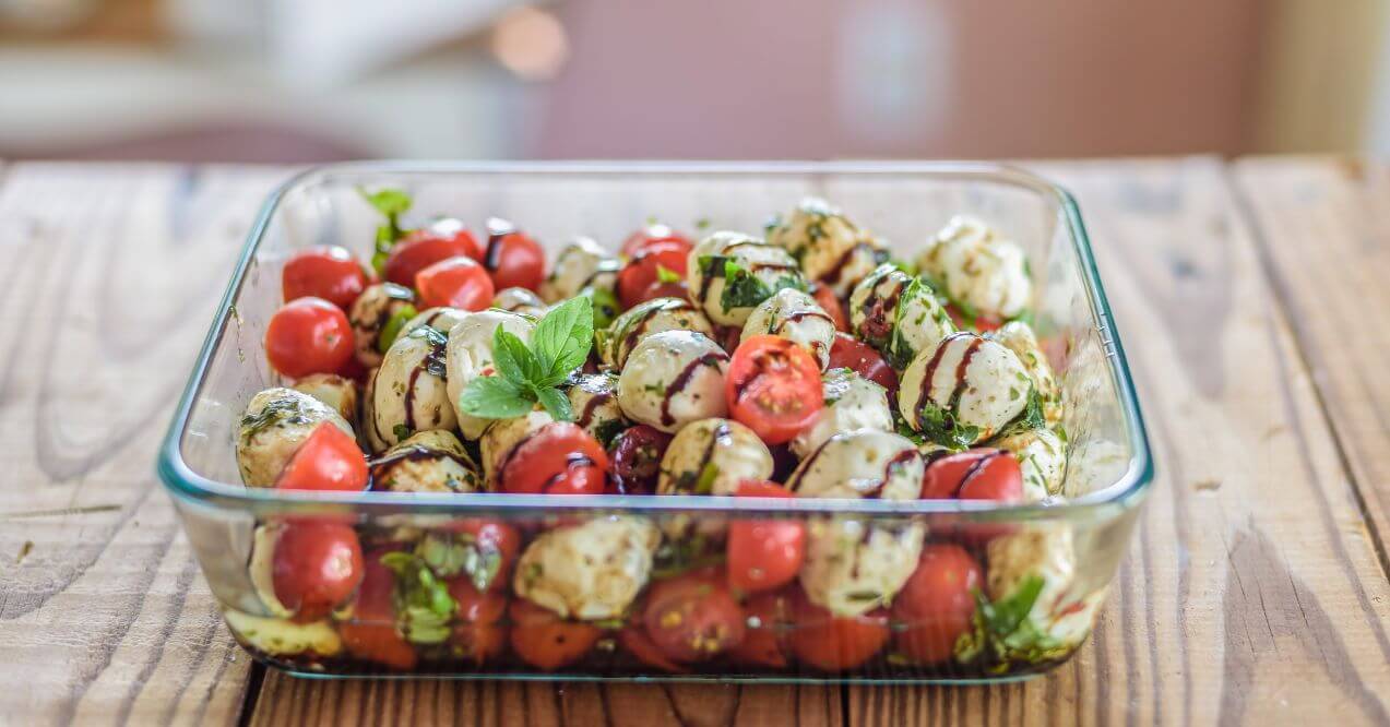 A bowl of cherry tomatoes and mozzarella drizzled with balsamic glaze.