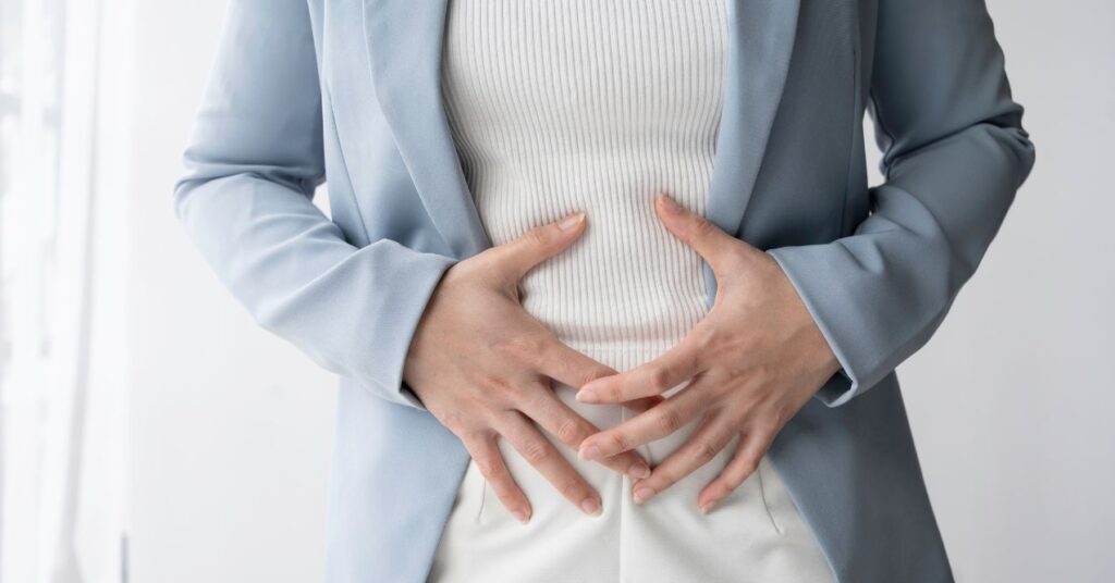 A person in discomfort holding their stomach.