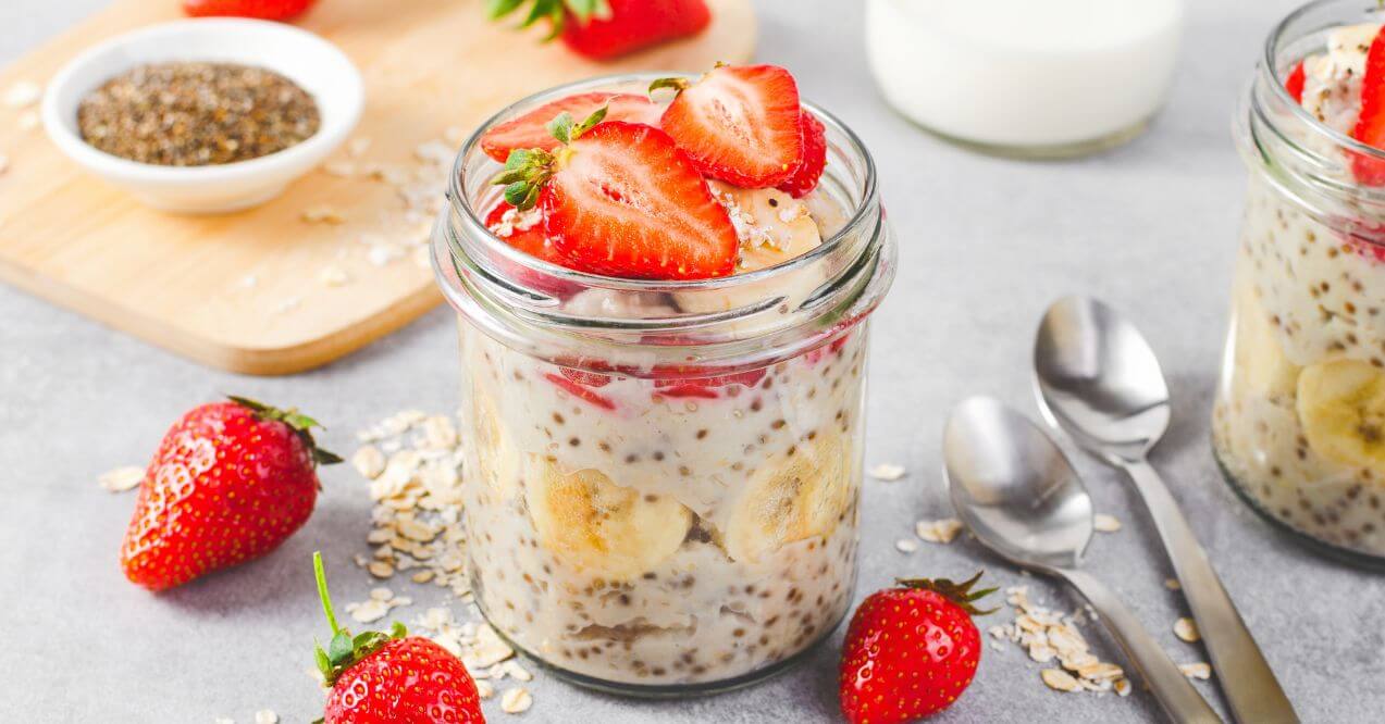 Jar of overnight oats topped with strawberries, banana slices, and chia seeds.